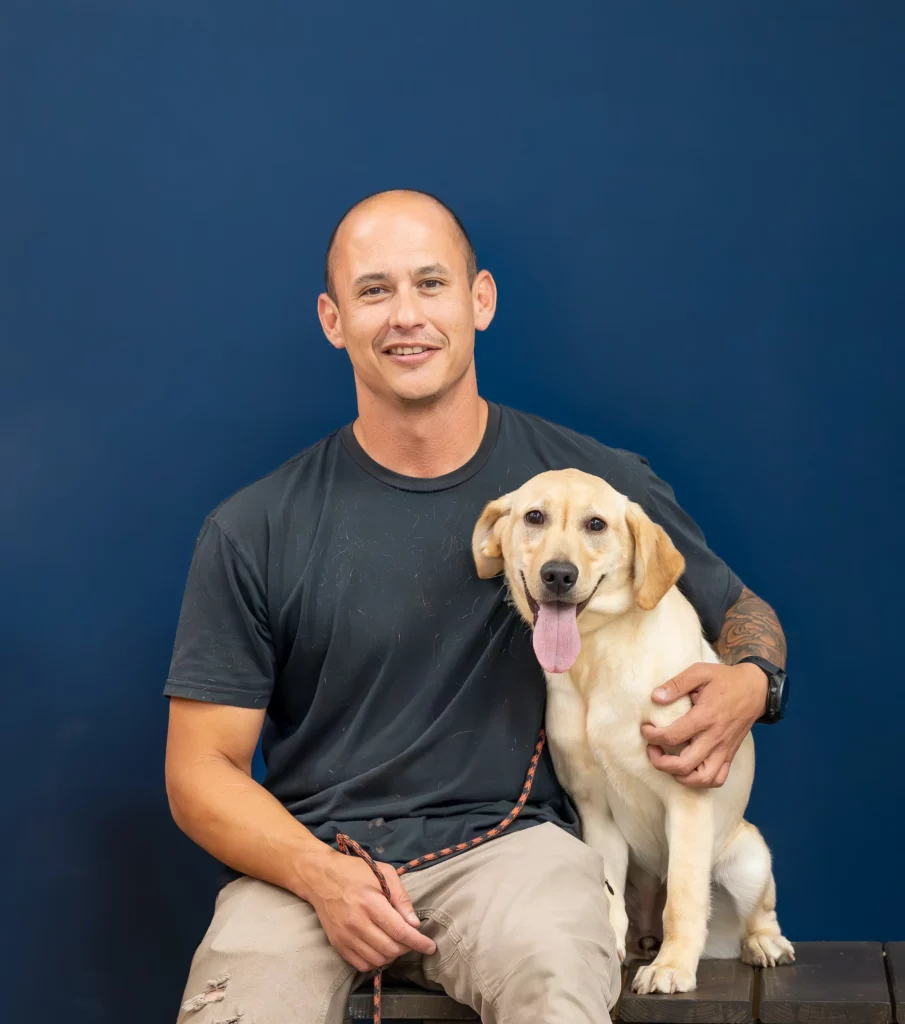 Andy, head dog trainer at OLK9 DFW and Marine Corps veteran, sitting with a yellow Labrador in Dallas-Fort Worth